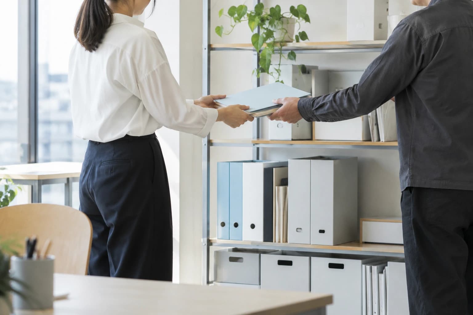 整理した業務資料を受け渡す作業（AI生成イメージ）