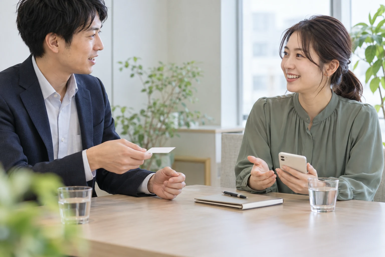 商談でスマートフォンとカードを使って自己紹介する場面（AI生成イメージ）